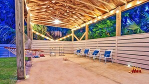 An outdoor covered area with a concrete floor, wooden beams, and a view of trees through the walls. - Island Adventures Await at the Pet Friendly “Boathouse SGI” (Saint George Island)