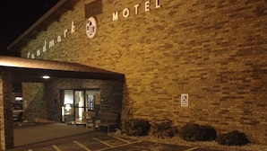 En byggnad av tegel med en skylt som visar texten ”Landmark Motel” och en parkeringsplats framför.