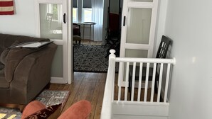 A living room with a brown couch, a red chair, and a white railing.