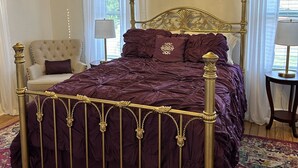 A luxurious bedroom with a large bed, ornate ceiling, and a chandelier.