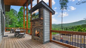 Una terraza de madera con mobiliario exterior y una chimenea de piedra.