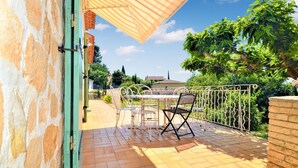 Eine Terrasse mit Tisch und Stühlen, eine Ziegelwand und ein Metallzaun.