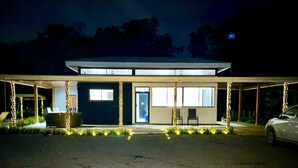 A modern building with a covered entrance, large windows, and a car parked in front. - Comfort in the Jungle (Sámara)