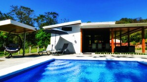A modern pool area with a clear blue pool, lounge chairs, and a covered seating area. - Comfort in the Jungle (Sámara)