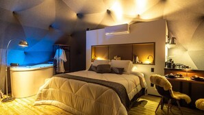 A modern bedroom with a large bed, bedside tables, a desk, and a chair. - Kairos Glamping - Rancho Queimado - SC (Rancho Queimado)