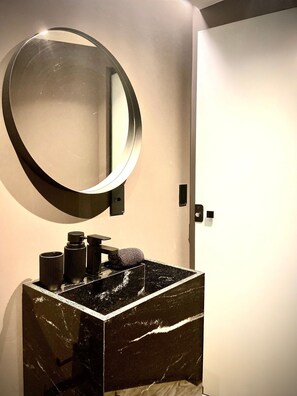 A bathroom with a marble sink, a round mirror, and a towel on the counter. - Kairos Glamping - Rancho Queimado - SC (Rancho Queimado)