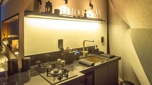 A modern kitchen with a built-in island, stainless steel appliances, and a unique textured wall. - Kairos Glamping - Rancho Queimado - SC (Rancho Queimado)