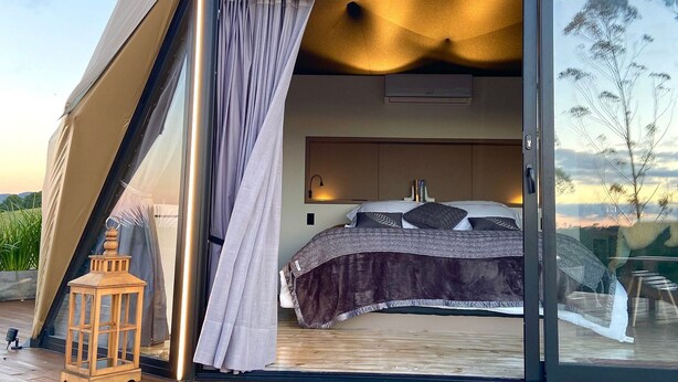 A tent-style accommodation with a bed, curtains, and a view of the outdoors. - Kairos Glamping - Rancho Queimado - SC (Rancho Queimado)