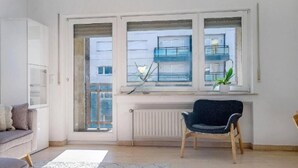 Eine moderne Wohnung mit großem Fenster, Heizkörper und einem dunkelblauen Sessel.