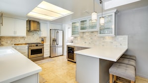 A modern kitchen with white cabinetry, stainless steel appliances, and a central island. - Private Pool & Spa: Indian Wells Home! (Indian Wells)