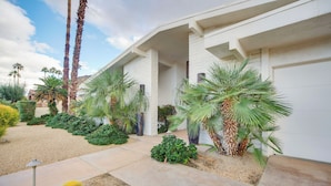 A modern house with a white exterior, a driveway, and various desert plants including cacti and palm trees. - Private Pool & Spa: Indian Wells Home! (Indian Wells)