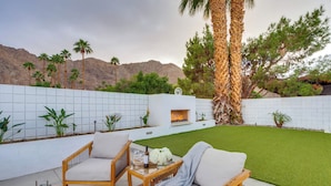 An outdoor seating area with a sofa and chairs, a small table with a bottle and glasses, and a fire feature. - Private Pool & Spa: Indian Wells Home! (Indian Wells)