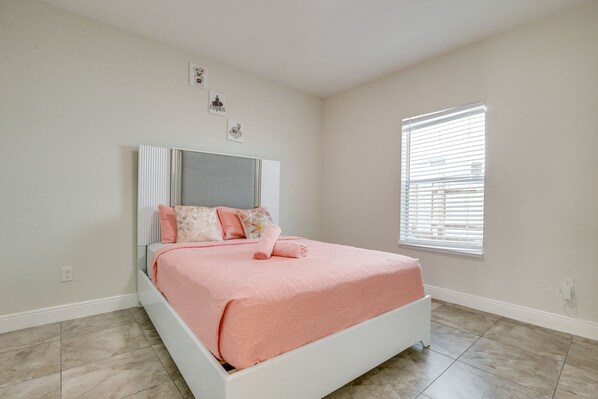 Un dormitorio con una cama, una ventana con persianas y una pared con tres cuadros.