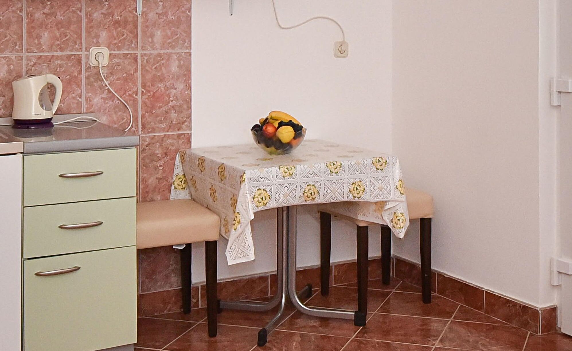 Eine kleine Küche mit Tisch, Wasserkocher und Obstschale.