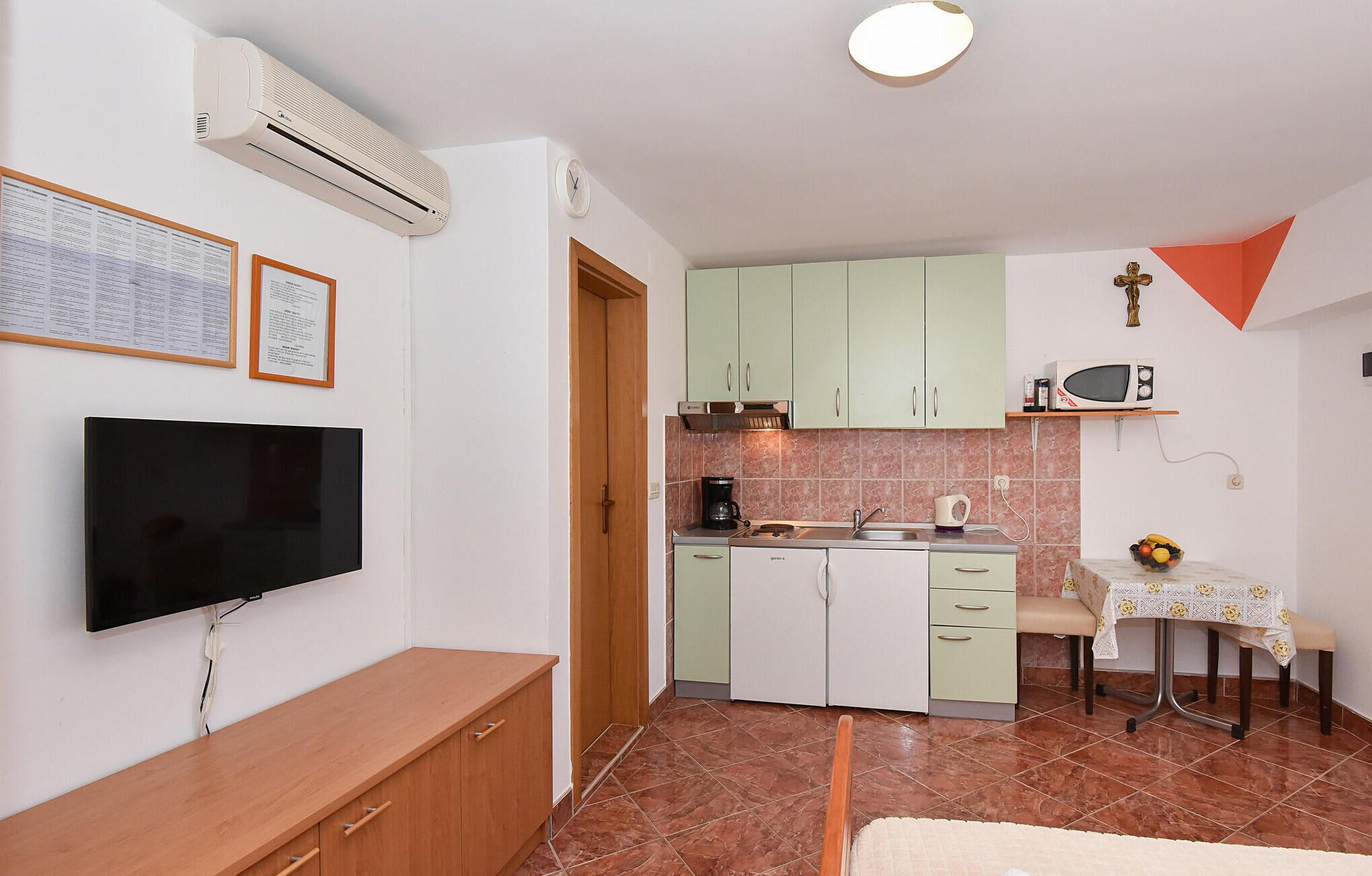 Una cocina compacta con televisión de pantalla plana, cafetera y microondas.
