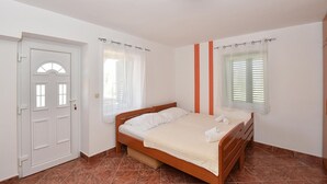 A bedroom with a bed, a door, a window with blinds, and a light fixture. - Stunning apartment in Privlaka with WiFi (Privlaka)