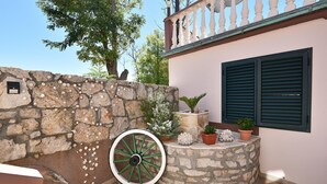 A stone wall with seashells, a green wheel, and potted plants. - Stunning apartment in Privlaka with WiFi (Privlaka)