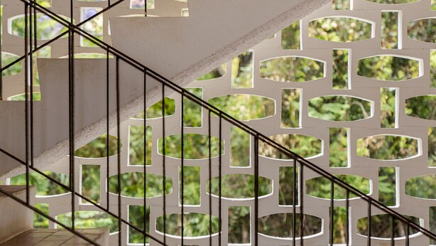 Un escalier doté d’une rampe aux motifs géométriques et offrant une vue sur la verdure environnante.