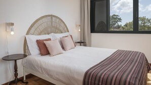 Une chambre à coucher avec un lit, des tables de chevet et une fenêtre donnant sur des arbres.