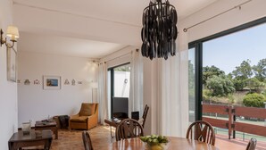 Un vaste espace de vie comprenant une table à manger en bois, des chaises, un canapé et un téléviseur.
