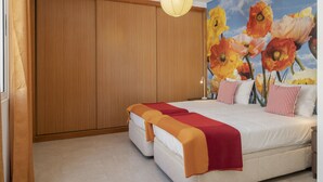 A bedroom with a large bed, wooden wardrobe, and a floral mural on the wall.