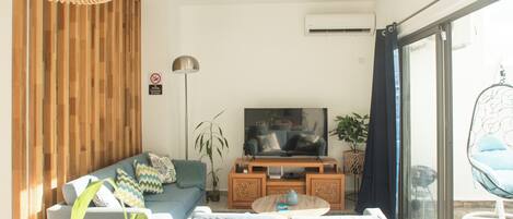 A modern living room with a sofa, TV, and a hanging chair.