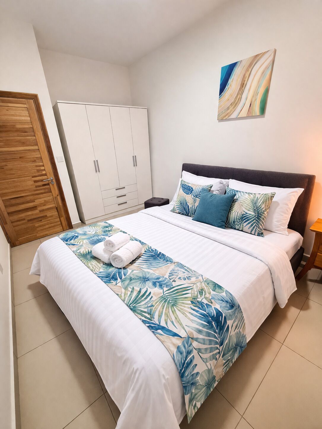 Une chambre à coucher avec un lit, une armoire, une table de chevet et un tableau au mur.