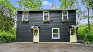 Ein zweistöckiges Haus mit dunkler Fassade, zwei gelben Türen und einem zentralen Fenster.