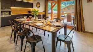 A modern kitchen with dark cabinets, a wooden countertop, and a dining area with a table set for four.