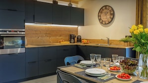A modern kitchen with dark cabinets, a wooden countertop, and a dining area set for a meal.