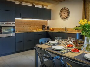 A modern kitchen with dark cabinets, a wooden countertop, and a dining area set for a meal.