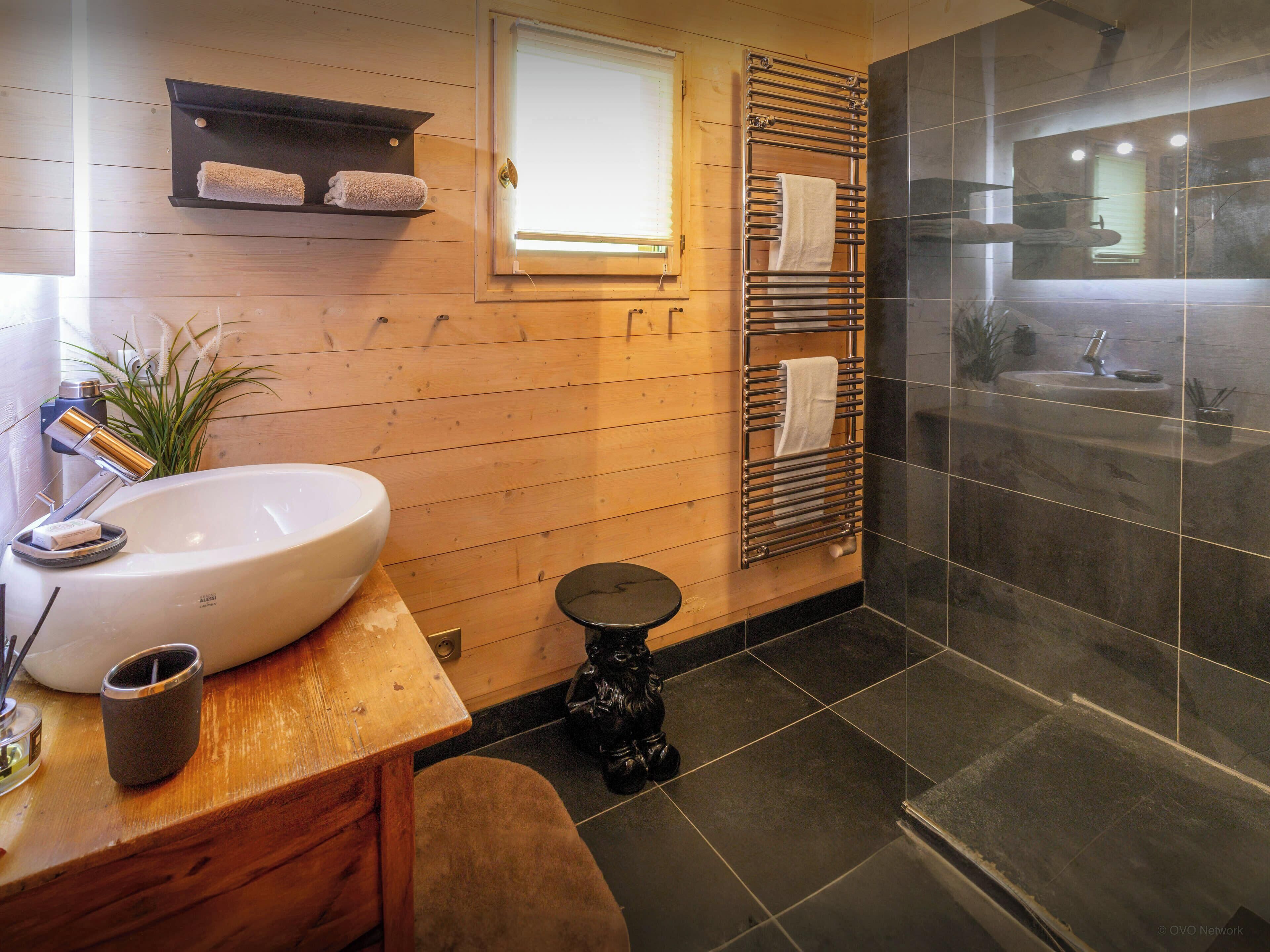 A modern bathroom with a wooden vanity, a large sink, a toilet, and a glass shower enclosure.