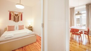 Une chambre d’hôtel avec un lit, une table de chevet, une lampe et une décoration murale en macramé.