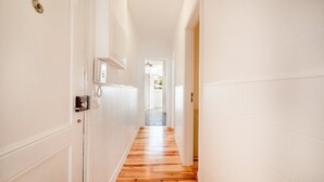 Un couloir aux murs blancs et au plancher en bois.
