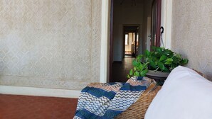 A room with patterned wallpaper, a bed with a patterned blanket, a potted plant, and a doorway leading to another room. - Beautiful penthouse with loggia and air conditioning, 100 meters from the sea. (Viareggio)