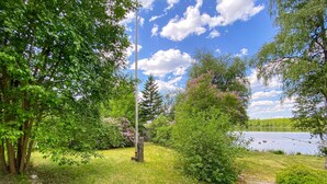 Un parc paisible au bord d’un lac, avec une pelouse, des arbres et un ciel dégagé.