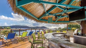 Une terrasse dotée d’un bar, de chaises et offrant une vue sur l’eau.