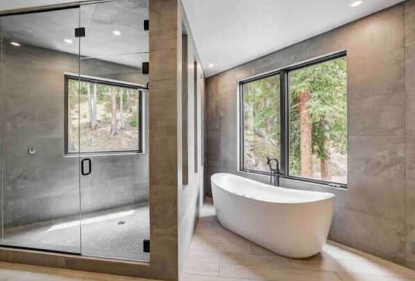 A modern bathroom with a freestanding bathtub, large windows, and a glass shower enclosure. - NEW! FULLY REMODELED Close to town and lifts. Huge rooms. Ski Hot tub!! (Breckenridge)