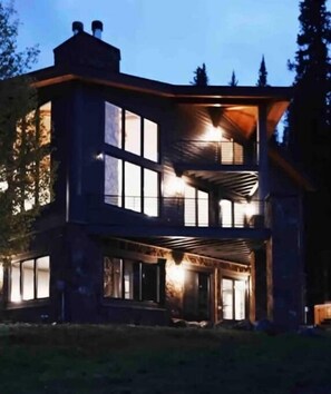Una casa moderna de dos pisos con ventanas grandes y un porche cubierto.