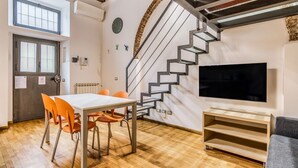 A modern interior with a staircase, a dining area, and a TV. - Ferrari Apartment Colonne (Milano)
