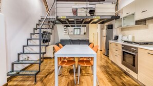 A compact kitchen with a dining area, a staircase, and a loft bedroom. - Ferrari Apartment Colonne (Milano)