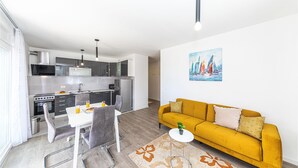 Eine moderne Küche mit Essbereich, einem gelben Sofa und einem Gemälde von Segelbooten an der Wand.