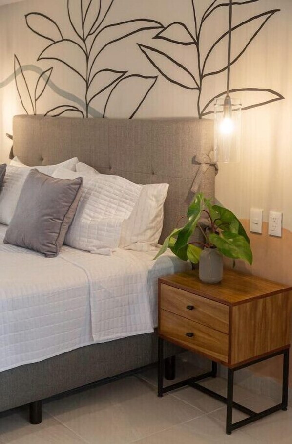 Une chambre à coucher avec un lit, une table de chevet avec une lampe et une œuvre d’art murale.