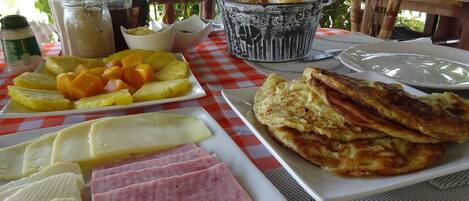 A breakfast table with plates of ham, cheese, pineapple, and toast.