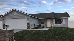 Ett enplanshus med ett garage, en veranda och ett litet garage som är sammanbyggt med huset.