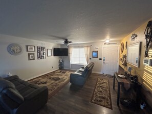 A living room with a ceiling fan, a television, a sofa, and a coffee table. - Perfect Space for a Comfortable Stay (Pasco)