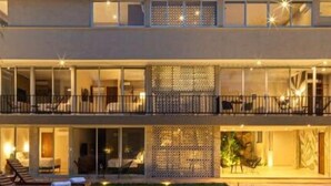 Un hôtel moderne doté d’une piscine, de nombreux balcons et d’un espace extérieur aménagé pour s’asseoir.