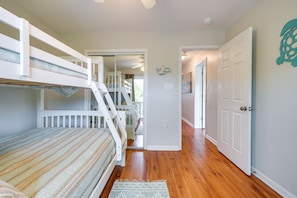 A room with bunk beds, a staircase, and a door leading to another room.