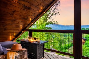 Une terrasse en bois avec une cheminée, un panier en osier et un chapeau.