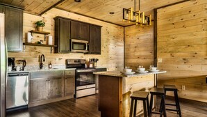 Une cuisine moderne avec des murs en bois, des appareils électroménagers en acier inoxydable et un îlot central doté de tabourets.